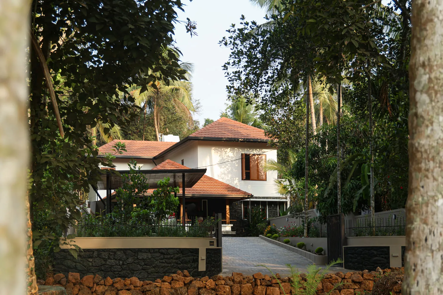 A tranquil house with a red-tiled roof surrounded by lush tropical foliage.