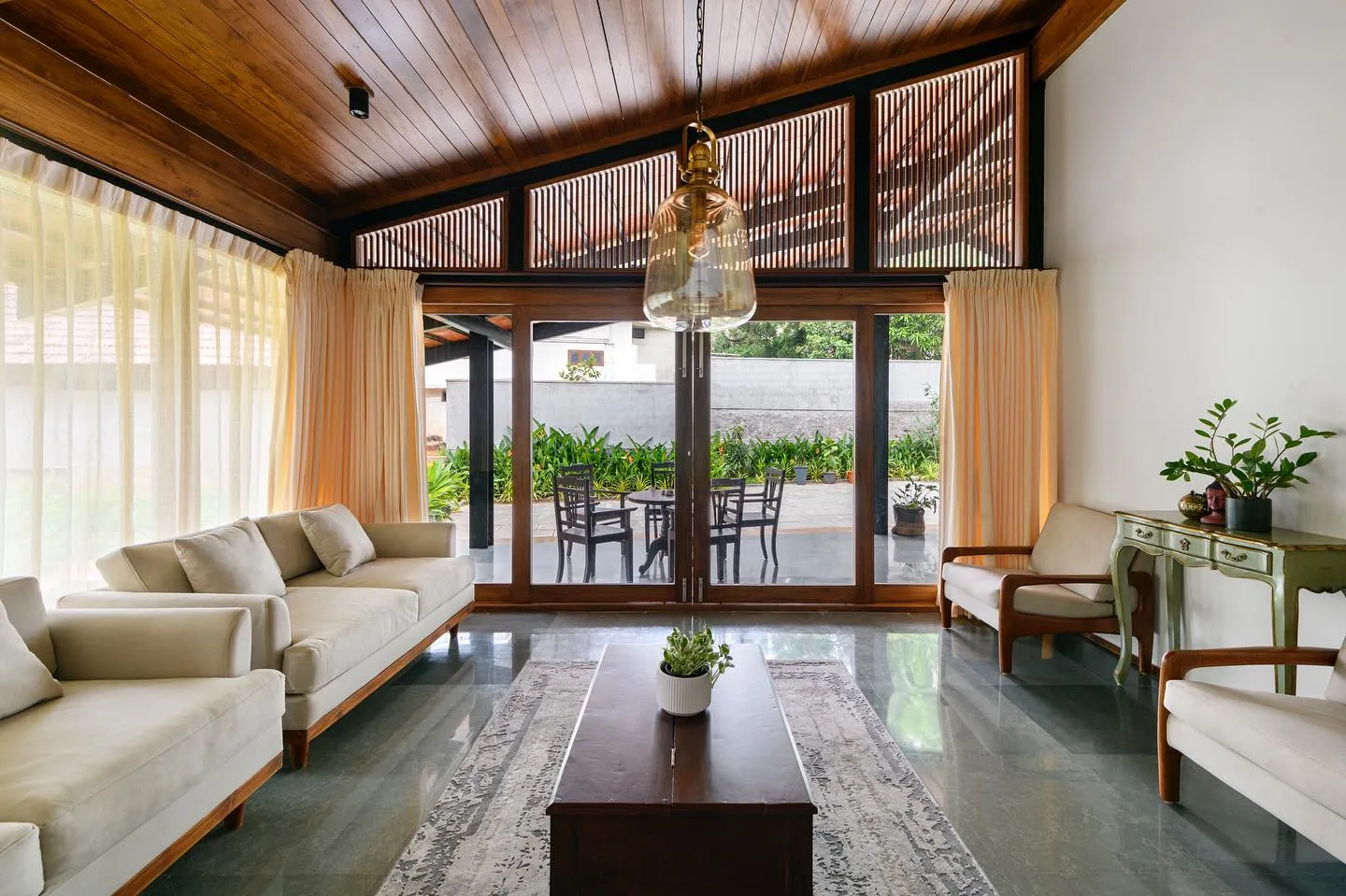 A cozy living room with wooden ceiling and expansive windows, bringing in natural light and warmth.