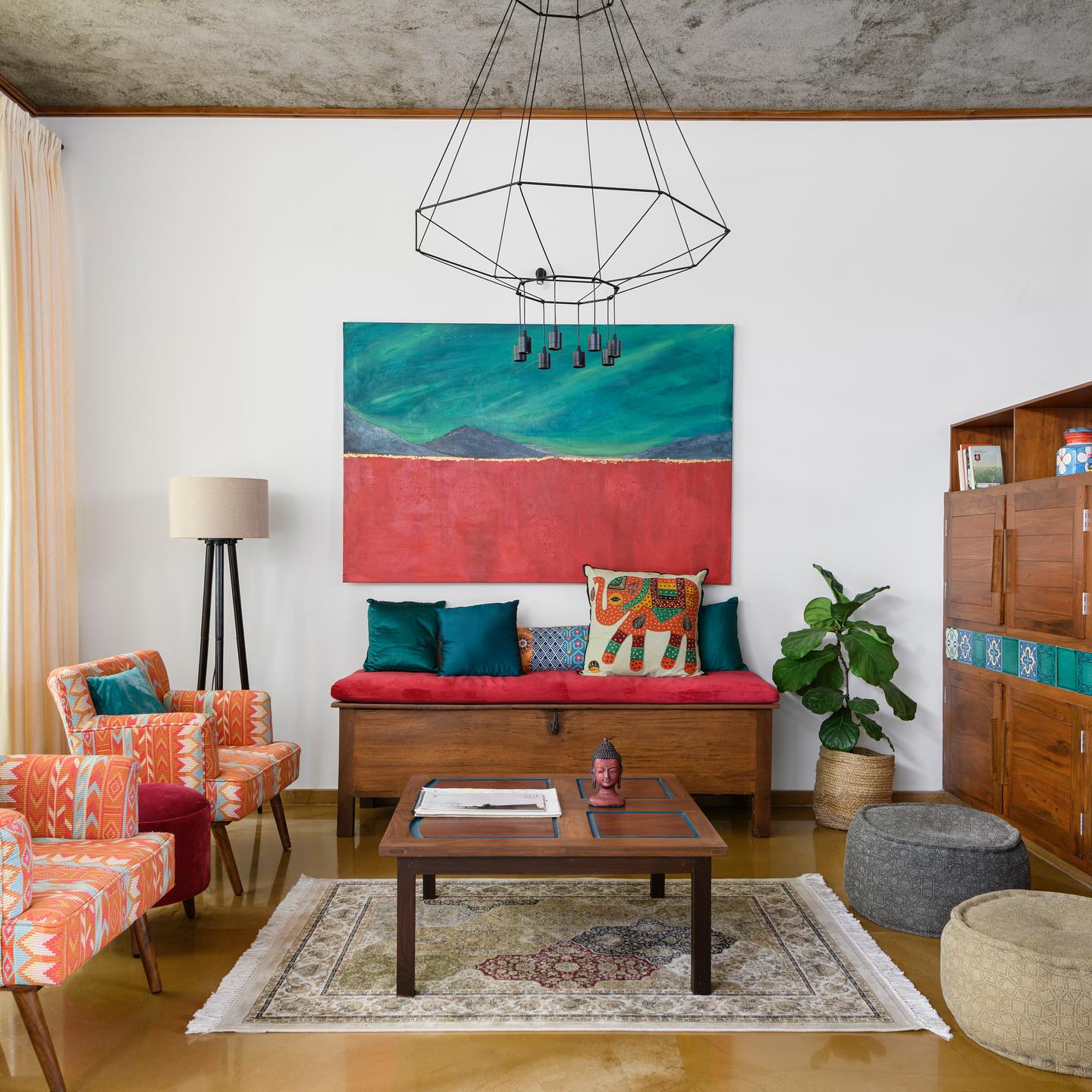 Colorful living room with eclectic decor, a red couch, patterned chairs, and large abstract painting.