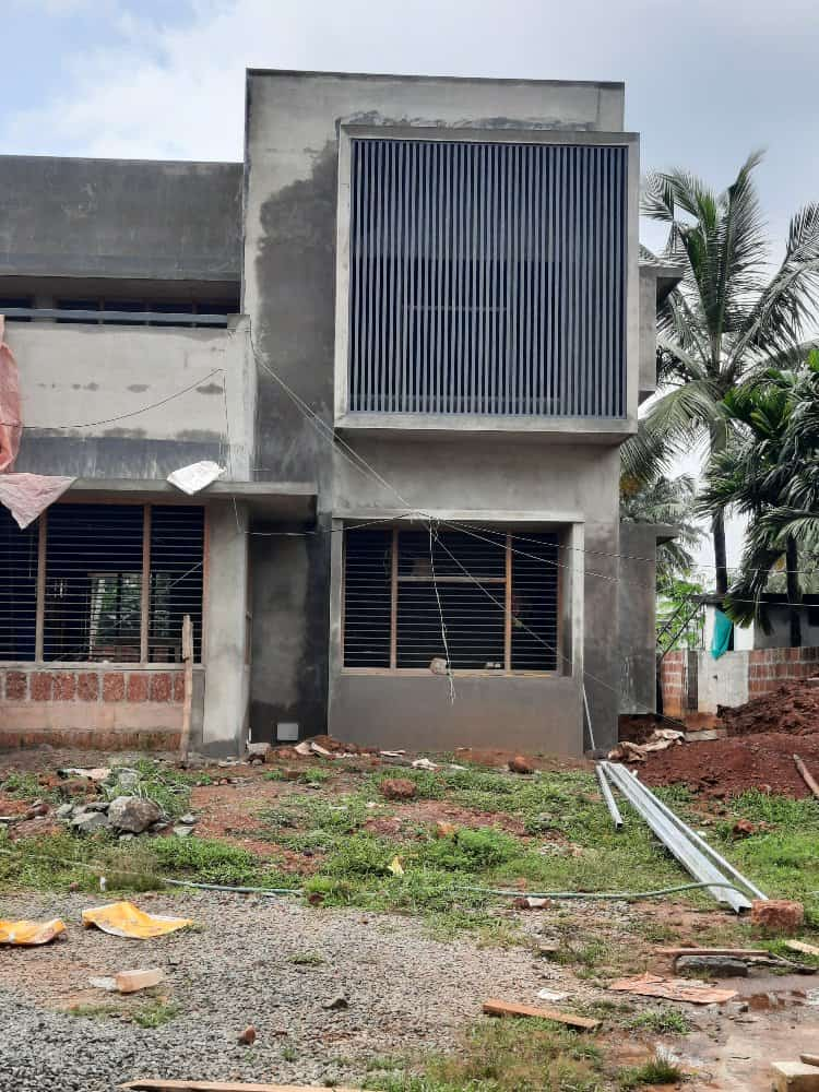 A house under construction with a large concrete wall in progress.