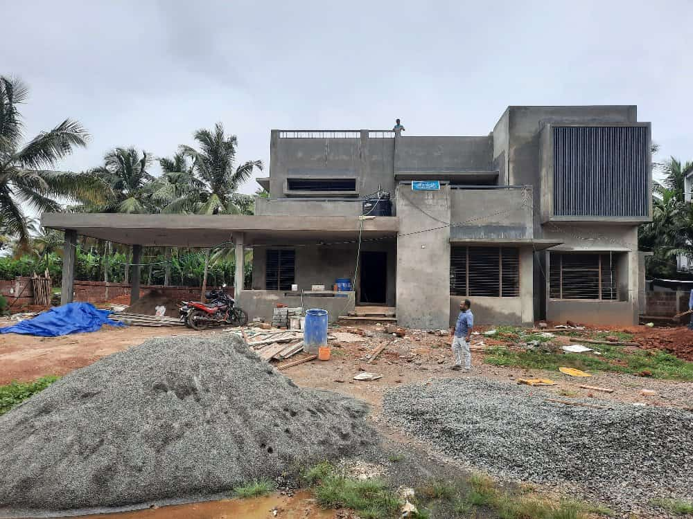 A new house under construction with workers busy building the structure under the clear blue sky.